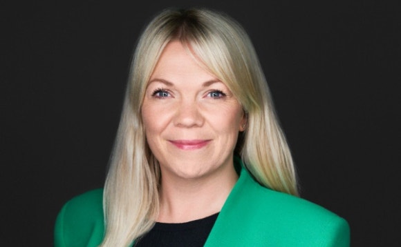 A person with blonde hair wearing a green jacket Description automatically generated