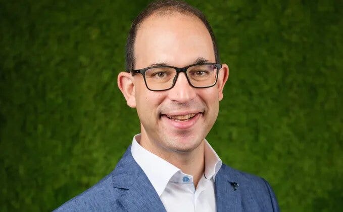 A person in a suit and glasses Description automatically generated