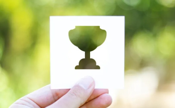 A hand holding a paper with a trophy AI-generated content may be incorrect.
