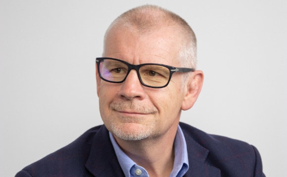 A person wearing glasses and a suit AI-generated content may be incorrect.