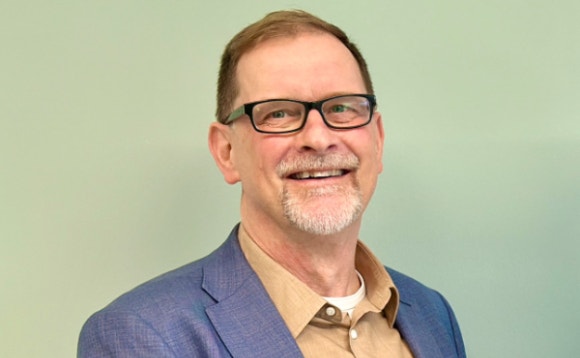 A person wearing glasses and a blue jacket AI-generated content may be incorrect.
