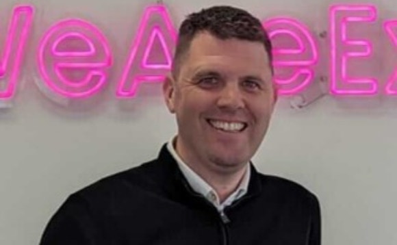 A person smiling in front of a sign AI-generated content may be incorrect.